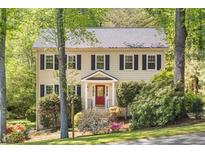 Charming two-story home with a red door and black shutters, surrounded by mature trees and lush landscaping at 2441 Mitchell Ne Rd, Marietta, GA 30062