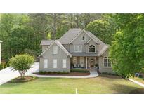 Beautiful home exterior with mature trees, well-manicured lawn, and welcoming front porch at 1315 Woodland Trce, Cumming, GA 30041