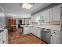 Traditional kitchen features white cabinetry, stainless appliances, and hardwood flooring at 4128 Mayflower Sw Ct, Lilburn, GA 30047