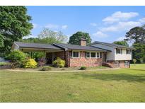 Charming brick home with a covered carport and a well-maintained front lawn under a sunny sky at 1548 Highway 81 W, Mcdonough, GA 30253