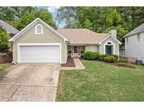 Charming home featuring a well-manicured lawn, complemented by a 2-car garage and a delightful pink front door at 1970 Glen Eves Dr, Roswell, GA 30076