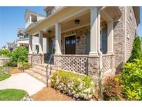 Charming front porch with brick accents, columns, and a welcoming entrance with beautiful landscaping at 168 Brighton Blvd, Woodstock, GA 30188
