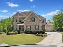 Beautiful two-story brick home with a well-manicured lawn and attached garage on a sunny day at 6090 Pennant Ln, Suwanee, GA 30024