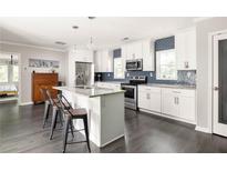 Bright kitchen featuring white cabinetry, stainless steel appliances, granite countertops, and a stylish island with seating at 1711 Terry Mill Se Rd, Atlanta, GA 30316