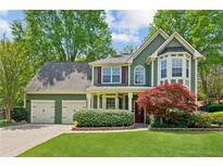 Charming two-story home featuring a lush front yard, two-car garage, and vibrant landscaping at 2267 Howell Farms Trl, Acworth, GA 30101