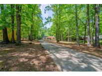 Ranch home with a charming front porch, nestled among mature trees and a long drive at 210 Meadowbrook Dr, Mcdonough, GA 30253