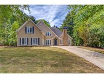 Charming two-story home featuring a manicured lawn, neutral siding, blue shutters, and a stone chimney at 12340 Preserve Ln, Alpharetta, GA 30005