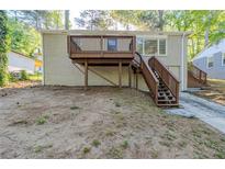Backyard of home featuring brick exterior, wooden deck with stairs, and partial landscaping at 2910 Diana Sw Dr, Atlanta, GA 30315