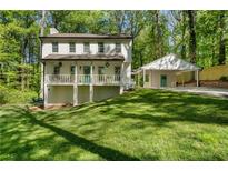 Charming two-story home featuring a spacious front porch and adjacent carport nestled in a wooded setting at 105 Woodmeade Nw Way, Marietta, GA 30064