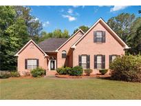 Charming brick home featuring a well-manicured lawn and inviting curb appeal with classic shutters at 219 Garden W Walk, Hampton, GA 30228