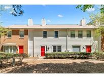Charming townhome featuring a brick and vinyl exterior, manicured landscaping, and inviting red front doors at 223 Chads Ford Way, Roswell, GA 30076