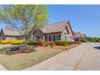 Charming brick home featuring a well-manicured lawn, mature tree, colorful shrubs and an inviting driveway at 4321 Lanier Ridge Walk # 1704, Cumming, GA 30041
