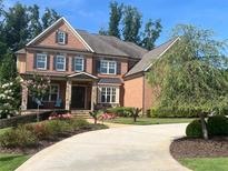 Stunning brick home featuring a manicured lawn, a circular driveway, and mature landscaping at 2331 Kinsale Nw Pt, Kennesaw, GA 30152