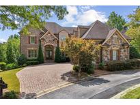 Beautiful brick and stone two-story home with a well-manicured lawn and circular brick driveway at 5422 Heyward Square Pl, Marietta, GA 30068