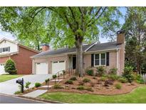 Charming brick home featuring a two-car garage, mature trees, and a well-manicured front yard at 1205 Club Walk Ne Dr, Brookhaven, GA 30319