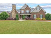 Charming brick home featuring a stone chimney, manicured lawn and mature landscaping at 416 Battlefield Creek Dr, Marietta, GA 30064