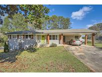 Charming exterior featuring a light grey brick facade, lime green front door, and covered carport at 2376 Falls River Dr, Lithia Springs, GA 30122