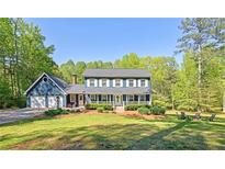 Charming two-story home with a well-manicured lawn and a welcoming front porch in a lush, wooded setting at 5830 Wills Wood Cir, Cumming, GA 30040