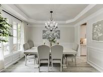 Elegant dining room features a decorative chandelier, table with seating, and large windows for lots of natural light at 7035 W Mountain Xing, Cumming, GA 30041