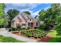 Charming brick home featuring a manicured front lawn, lush landscaping, and a welcoming entrance at 7050 Redcliff Ct, Suwanee, GA 30024