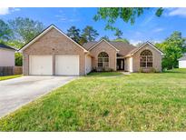 Charming brick home featuring a two-car garage and well-maintained lawn at 6687 Hill Creek Cv, Lithonia, GA 30058