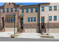 Three-story brick townhouses with attached garages and professional landscaping line the street at 243 Commons Ave, Woodstock, GA 30188