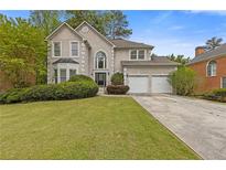 Charming two-story traditional home featuring a manicured lawn, attached two-car garage, and lush, mature landscaping at 861 Southland Pass, Stone Mountain, GA 30087