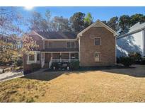 Traditional brick home with a covered front porch and well-maintained lawn, exuding curb appeal at 5000 Bainbridge Sw Ct, Lilburn, GA 30047