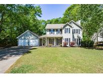 Charming two-story home with a lush green lawn and a detached two-car garage, surrounded by mature trees at 605 Sutton Sw Way, Marietta, GA 30064