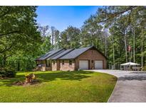 Charming single-story brick home featuring an attached two-car garage and a sprawling front lawn with mature trees at 3400 Bonds Lake Nw Rd, Conyers, GA 30012
