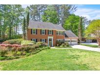 Charming brick home featuring a manicured lawn, black shutters, and an attached two car garage at 2830 Scottish Mill Way, Marietta, GA 30068