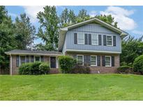 Split level home with a brick and blue facade, shuttered windows, and a well-manicured lawn at 5618 Fern Creek Sw Dr, Lilburn, GA 30047