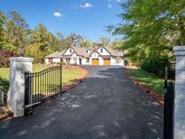 Stately white home with wood trim, garage, and automatic gate on long asphalt driveway at 3920 Maybreeze Rd, Marietta, GA 30066