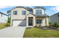 Charming two-story home featuring a brick facade, well-manicured lawn, and an attached two-car garage at 802 Milo Bay St, Loganville, GA 30052