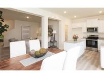 Bright dining area with wood table, white chairs, and an open view of the modern kitchen and comfortable living room at 2680 Ne Almand Ne Ln, Conyers, GA 30013