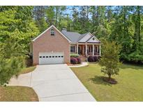 Charming brick home featuring a columned front porch and a well-manicured lawn at 5071 Woodmont Dr, Villa Rica, GA 30180