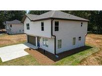 New two-story home with white siding, a dark roof, an attached two-car garage, and a concrete driveway at 1341 E Atlanta E Rd, Stockbridge, GA 30281