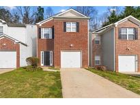 Charming townhouse featuring a brick facade, single car garage, and well-maintained front lawn at 2825 Windsor Forrest Ct, Atlanta, GA 30349