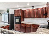 This is a kitchen with dark wood cabinets, stainless steel appliances, and granite countertops at 900 Stone Lea Trce, Oxford, GA 30054