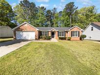 Charming single-story brick home with a well-manicured lawn and attached two-car garage at 6028 Arbor Links Rd, Lithonia, GA 30058