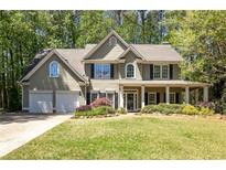 Charming two-story home with manicured lawn, two-car garage, and welcoming front porch with columns at 384 Wesley Dr, Acworth, GA 30101
