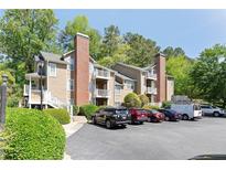 A tan building with a brick chimney and multiple balconies, surrounded by green trees and a parking lot in front at 5566 River Heights Se Xing, Marietta, GA 30067