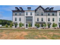 Modern townhomes with white brick, gray accents, dormer windows, and professionally landscaped front yards at 529 Rubato Knl, Mcdonough, GA 30253
