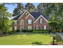Traditional brick home with well-manicured lawn, lush landscaping, and a welcoming front entrance at 7115 Doncaster Ct, Cumming, GA 30040