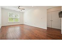 Bright living room featuring hardwood floors, a ceiling fan, and a large window for natural light at 10 Perimeter Summit Ne Blvd # 2207, Brookhaven, GA 30319