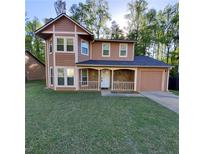 Charming two-story home featuring a covered porch with stone accents and an attached one car garage at 3267 Forette Ln, Lithonia, GA 30038