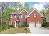 Charming red brick home featuring a two-car garage and manicured front yard at 455 Cooper Woods Se Ct, Smyrna, GA 30082