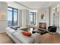 Bright living room with a large sectional sofa, fireplace, and city views from the expansive windows at 3376 Peachtree Ne Rd # 44B, Atlanta, GA 30326