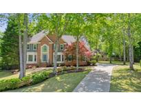 Beautiful brick home featuring a well-manicured lawn, mature trees, and a long driveway at 120 Stanmore Ct, Roswell, GA 30075