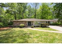 Charming single-story home with stone accents, a well-manicured lawn, and mature trees creating a private setting at 239 Devonwood Dr, Atlanta, GA 30328